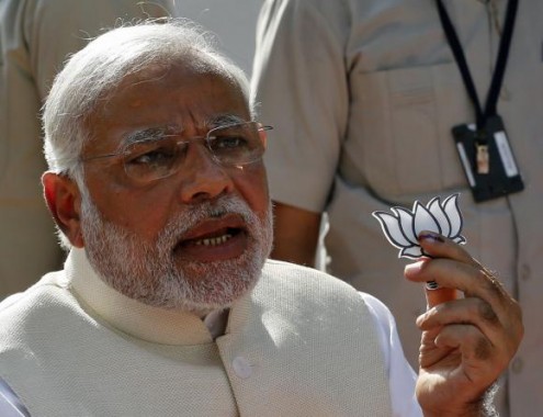 Hindu nationalist Modi holds a lotus cut-out after casting his vote at a polling station in Ahmedabad