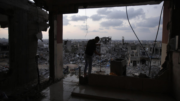 A Palestinian man cleans his house that witnesses said was heavy shelled by Israel during the offensive, in the Shejaia neighbourhood east of Gaza City