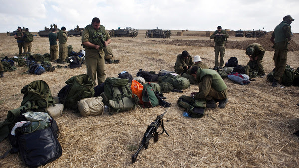 Israeli army reservists check their gear in a staging area outside the Gaza Strip